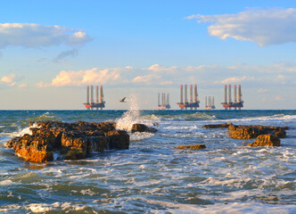 Sunset over the raging sea. Sea station of gas production. Drilling platforms in the sea at sunset...