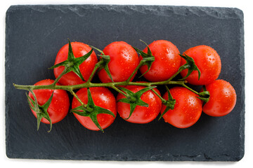 Cherry tomatoes on a slate cutting board, isolate on a white background.