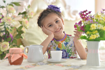 Smiling little girl holding big cup of tea