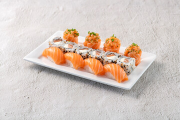 Fresh made sushi mix. Different kinks of salmon sushi served on white plate. Studio shoot on slated...