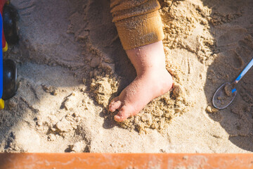 Toddler baby playing concept: Cut out of young boy playing in the sandbox, summer time