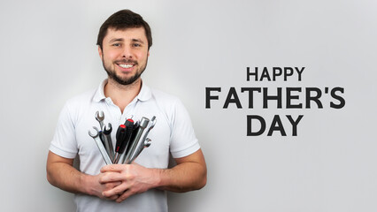 Smiling happy bearded man with bouquet of wrenches, spanners and screwdrivers with inscription happy father's day. Happy fathers day concept or greeting card