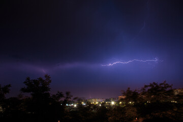 Lightning discharges over the city. A summer thunderstorm at night.