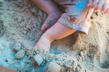 Toddler baby playing concept: Young boy playing in the sandbox, summer time