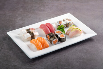 Sushi mix on white plate. Studio shoot isolated on slate background. Salmon, tuna, octopus and...