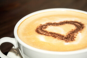 Coffee drink on a wooden table. Heart in coffee. Aromatic coffee
