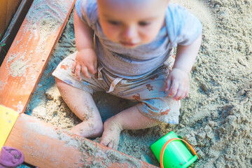Fototapeta premium Toddler baby playing concept: Young boy playing in the sandbox, summer time