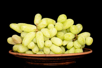 One bunch of white seedless grapes on a clay dish, close-up, isolated on a black background.