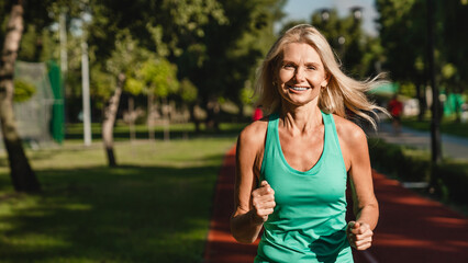 Closeup cropped shot of a female caucasian mature woman running jogging outdoors looking at camera. Slimming workout training