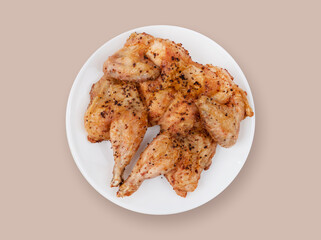 Baked chicken in spices on a white plate on a beige background. Top view