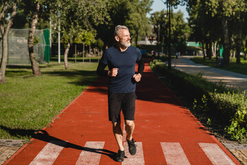 Full length portrait of a smiling confident mature caucasian runner athlete sportsman jogging...