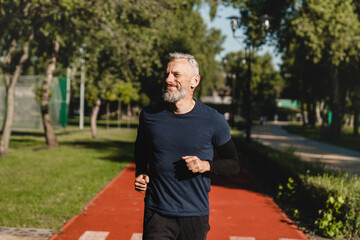 Smiling confident mature caucasian runner athlete sportsman jogging running in the morning on...