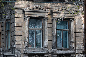 Side view of an old wooden apartment building in Nizhny Novgorod. Windows with antique stucco in the form of pillars crumbled by time, curtains and pots with flowers on the windows