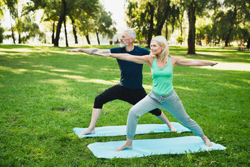 Fitness trainer instructor coach meditating stretching with mature woman on sporty mats during yoga...