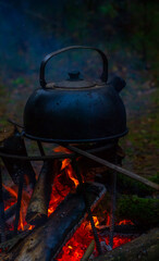 an old camping kettle is heated on a fire