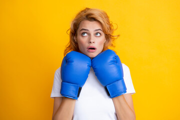 Funny surprised woman in boxing gloves isolated on yellow background.