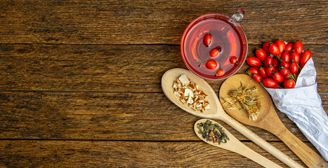 herbal tea cup Dog rose, bunch branch Rosehips, types Rosa canina hips, dry tea leaves . Medicinal plants and herbs composition