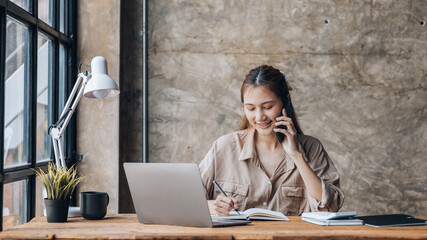 Asian woman talking on the phone, she is a salesperson in a startup company, she is calling...