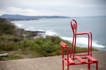Red steel chairs on top of old bunker in southern france with a view of the pyrenees mountains