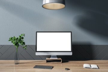 Front view on computer monitor with white blank screen on dark wooden table with black keyboard, notebook and glass vase in sunny room with dark wall. 3D rendering, mockup