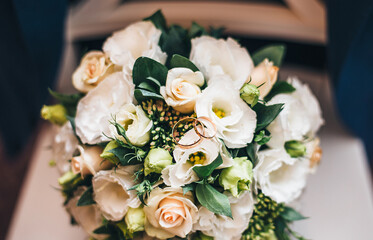 wedding rings on a bouquet of light rose flowers. wedding decor holiday