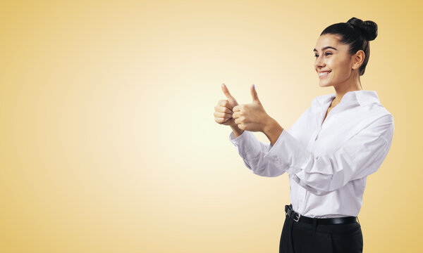 Like concept with happy young woman in white shirt holding thumbs up on light orange wall background with empty place for you text, mock up