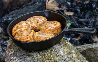 cinnamon buns cooked in cast iron pan outside on a fire
