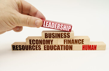 On a white background, the hand adds blocks with inscriptions on a red block, the inscription - LEADERSHIP