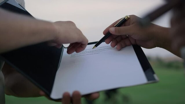 Businessman hands sign paper deal on nature. Investors write contract outdoors.