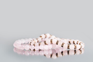 Two bracelets made of natural pink quartz stones beads isolated on gray background. Handmade...