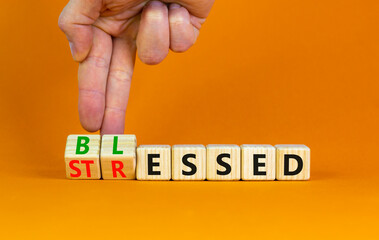 Blessed or stressed symbol. Businessman turns wooden cubes and changes the concept word Stressed to Blessed. Beautiful orange table orange background. Business blessed or stressed concept. Copy space.