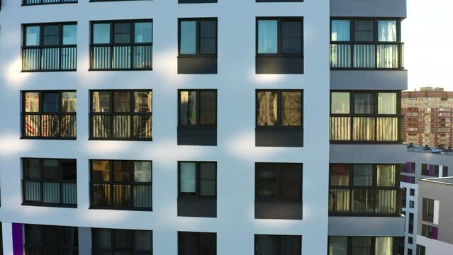 Dark windows of the white multi-storey building. Stock footage. Aerial view of an apartment residential skyscrapers on a summer sunny day.