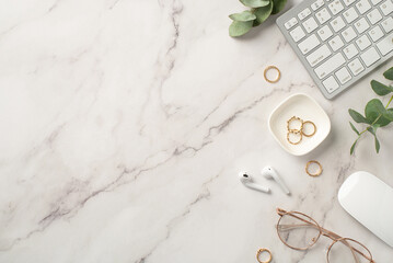 Business concept. Top view photo of workspace keyboard computer mouse wireless earbuds gold rings stylish glasses and eucalyptus on textured white marble background with copyspace