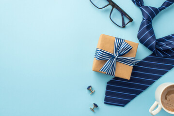 Father's Day concept. Top view photo of craft paper giftbox with ribbon bow cup of coffee spectacles cufflinks and blue necktie on isolated pastel blue background