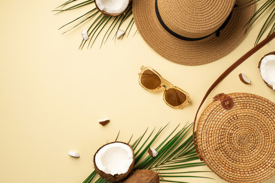 Summer vacation concept. Top view photo of sunhat round rattan bag sunglasses cracked coconuts and green palm leaves on isolated beige background