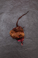 Ugly beet on dark stone surface, selective focus, copy space. Concept- Reduction organic food waste