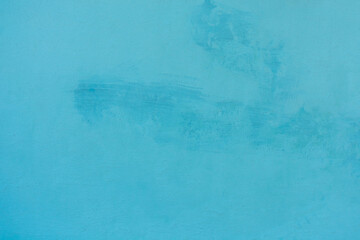 Photo of a wall with an aged rough texture of plaster painted in light blue