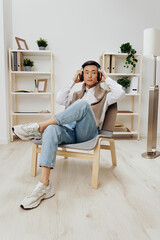 Asian man in headphones sits on a chair rest music Lifestyle