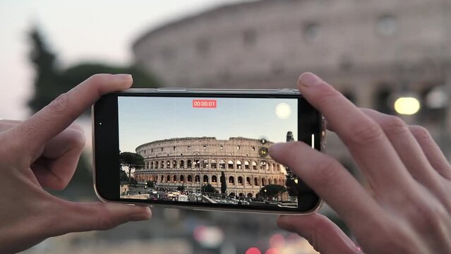 Tourist takes a smartphone video of the Colosseum in Rome Italy .