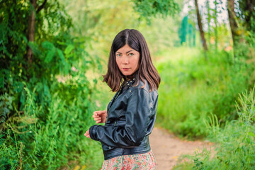 a young girl with black hair stands in the middle of the green forest