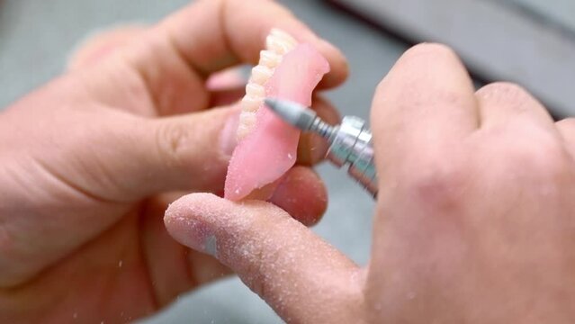 dental technician works in his workshop and makes artificial teeth for dentistry. in the frame are the hands of the master and the teeth created by the specialist. Slow motion