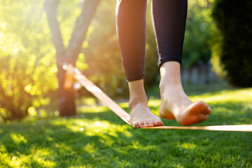 woman walking on a slackline in a park at sunset. core balance training