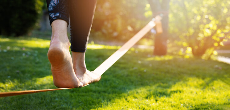 person walking on a slackline barefoot. strength and balance exercises