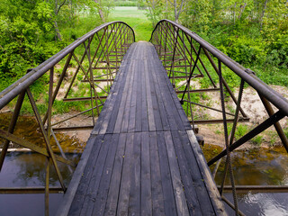 Obraz premium Pedestrian wooden bridge with railings over Ciecere river, Latvia.