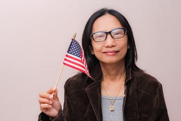Asian woman with glasses holding an American flag.