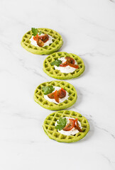 Round spinach waffles with cottage cheese, cherry tomatoes and parsley. Light background