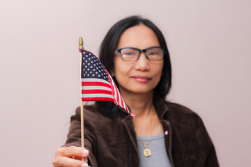 Asian woman with glasses holding an American flag.