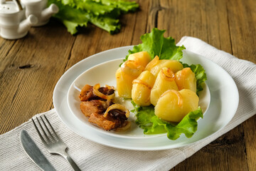 whole boiled potatoes with bacon and onions, cracklings and fried onions, on a wooden table, lettuce and fresh vegetables, the sun's rays, a minimum of objects in the frame, top view, a fork and a spo