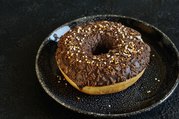 Delicious chocolate donut close-up on a concrete background in black. Selective focus, daylight