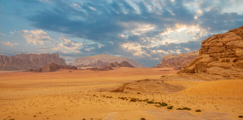 Fototapeta na wymiar Red sands, mountains, dramatic sky and marthian landscape panorama of Wadi Rum desert, Jordan